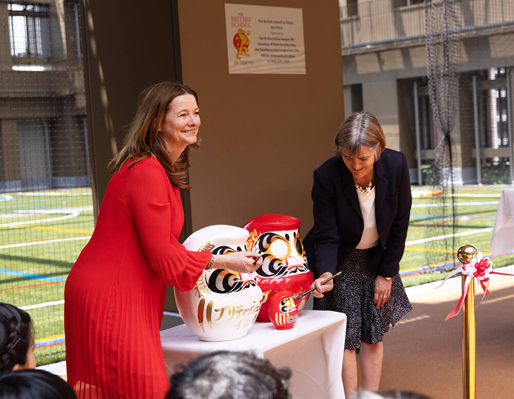 だるまの目入れをするジリアン・キーガン英国教育大臣とジュリア・ロングボトム駐日英国大使