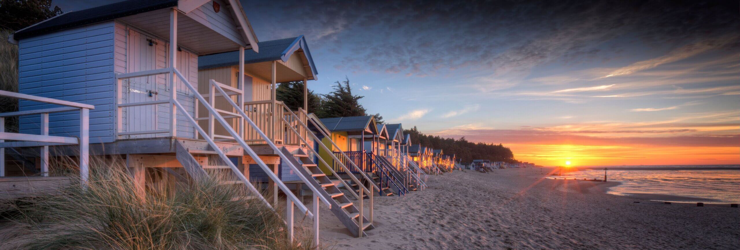 Sunset at high tide behind the old beach huts at Wells-next-the-sea on the North Norfolk coast.