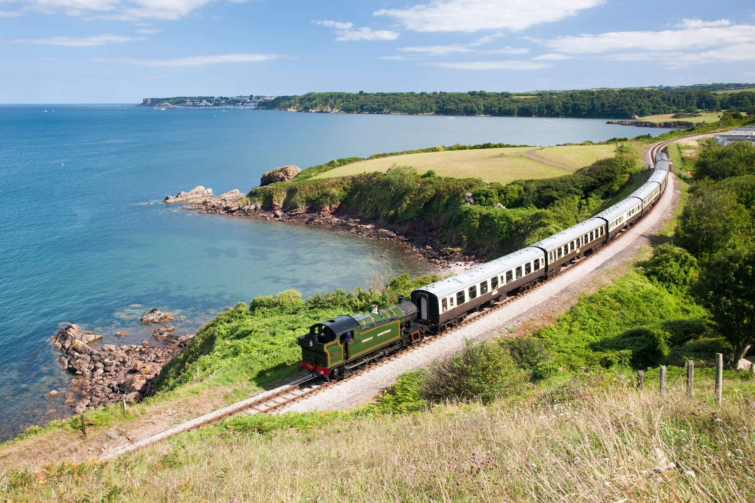 Steam train on the Dartmouth Steam Railway line, approaching Churston running along the coastline.