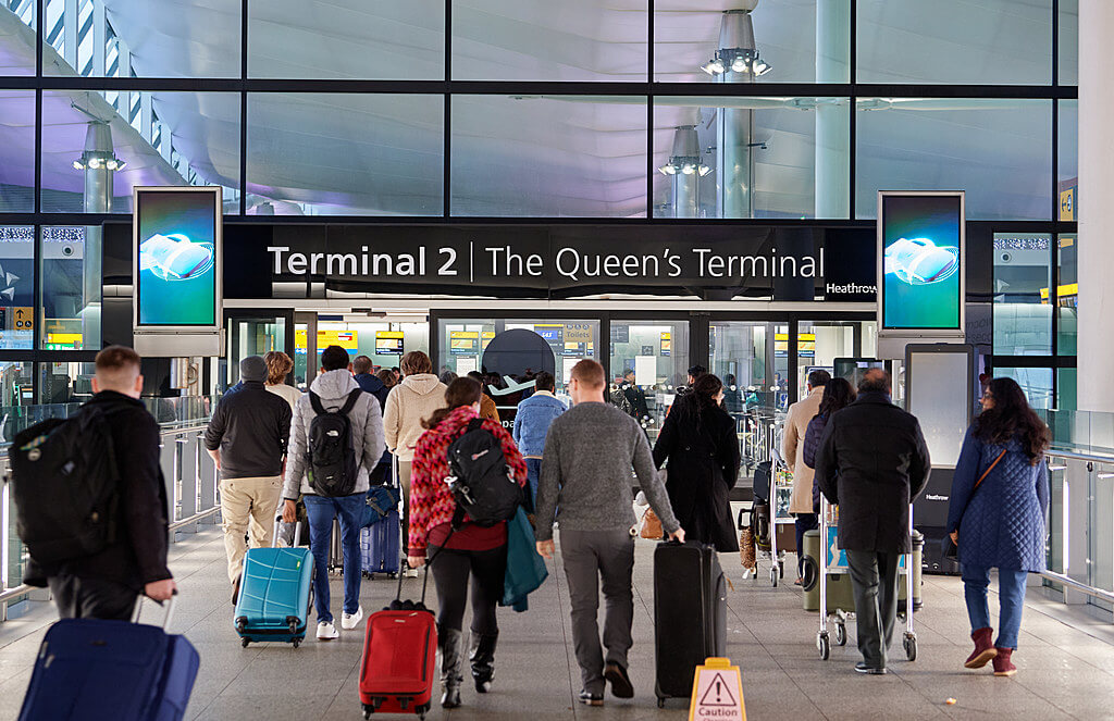 Passengers with luggage arriving at London Heathrow Airport Terminal 2.