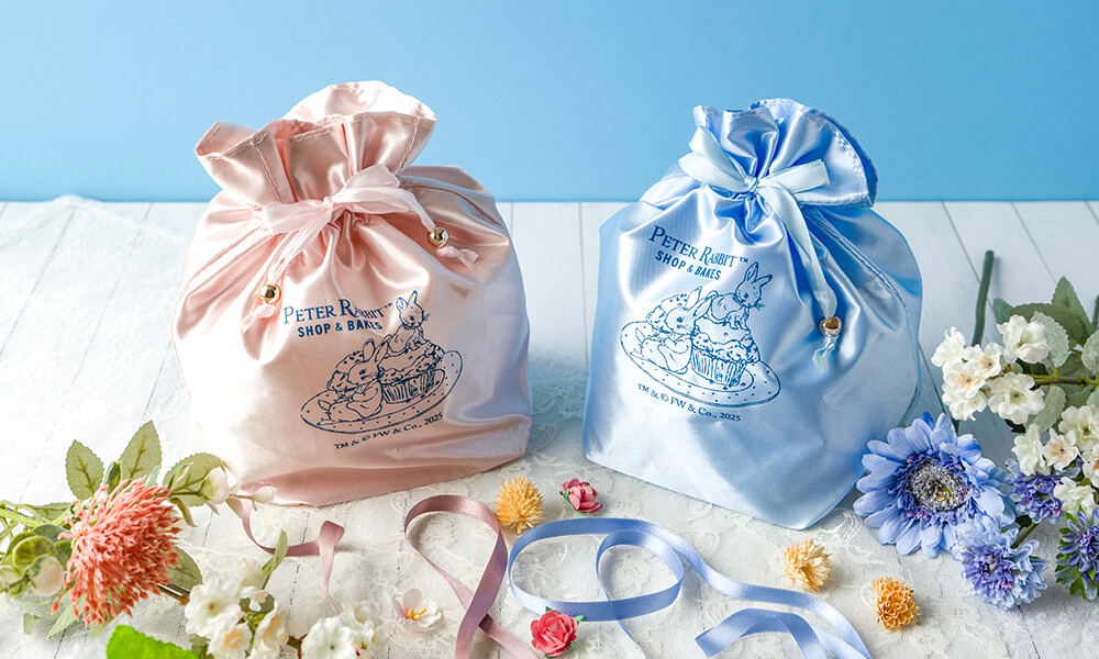 左から、軽井沢店限定ノベルティサテンキューブ巾着（ピンク）、二寧坂店限定ノベルティサテンキューブ巾着（ブルー）