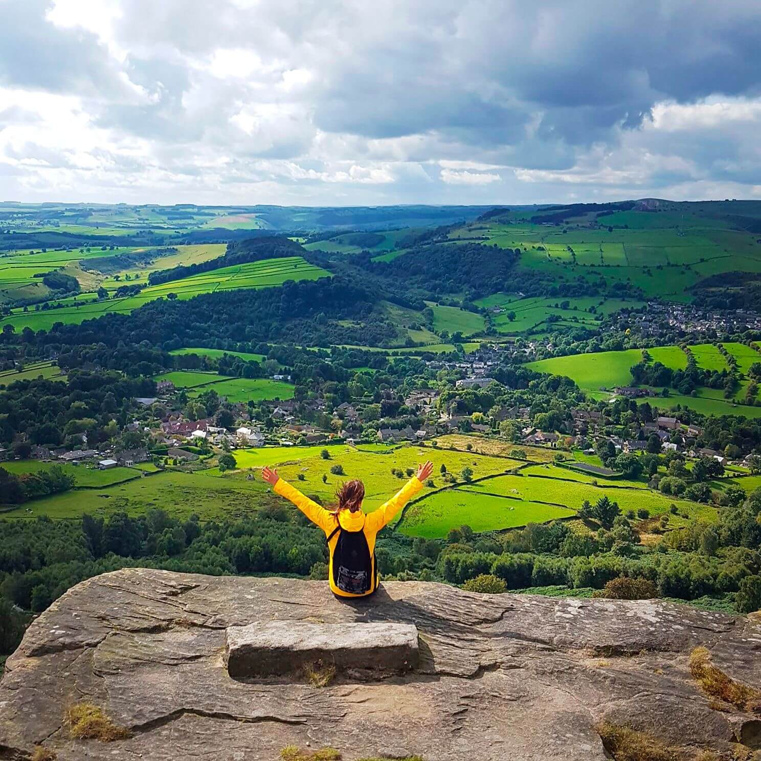 A woman with her arms raised enjoying the view from Curbar Edge, Hope Valley,Peak District, Derbyshire, England.