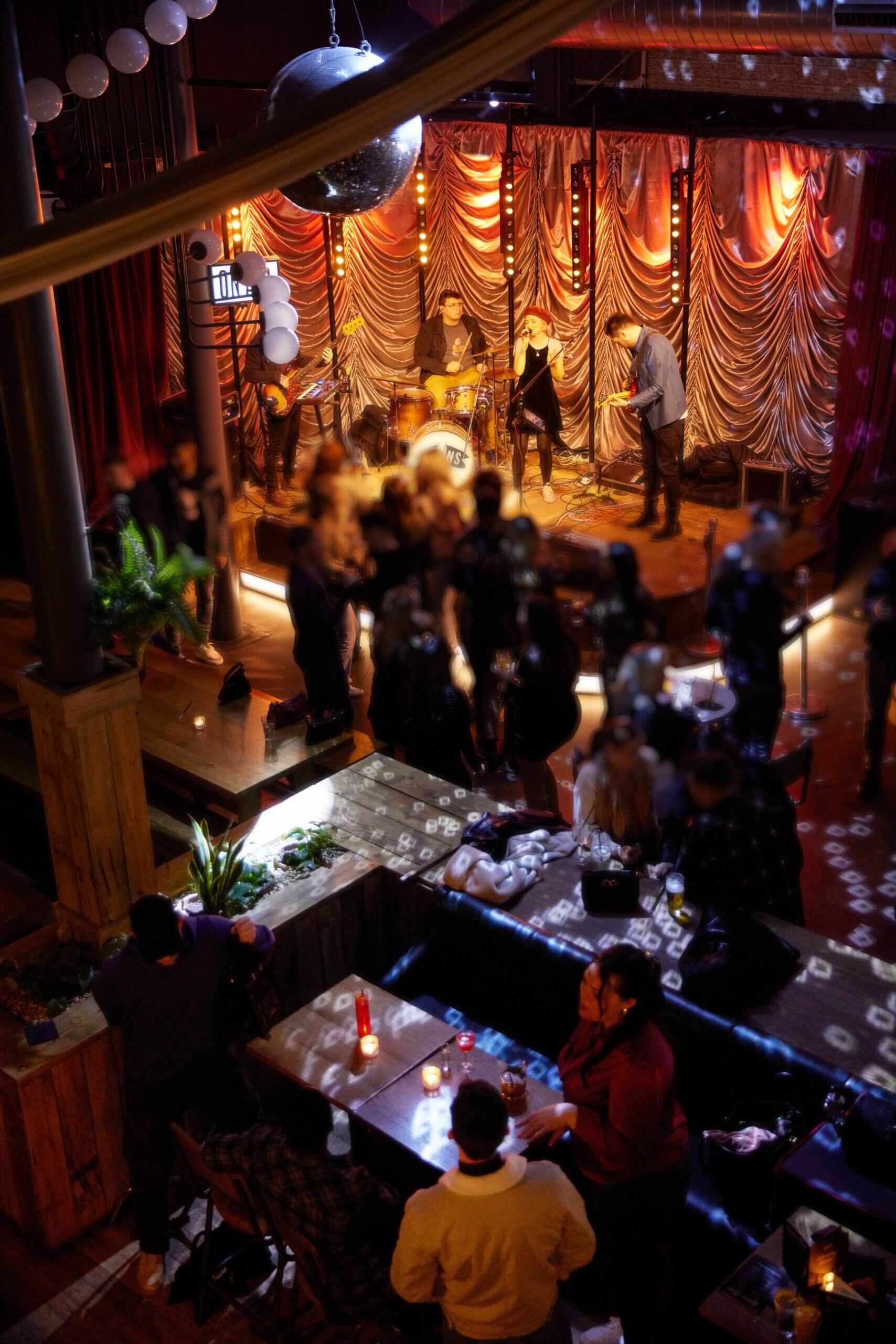 A group of friends enjoying a night out at a bar with live band at PINS Social Club, Liverpool.