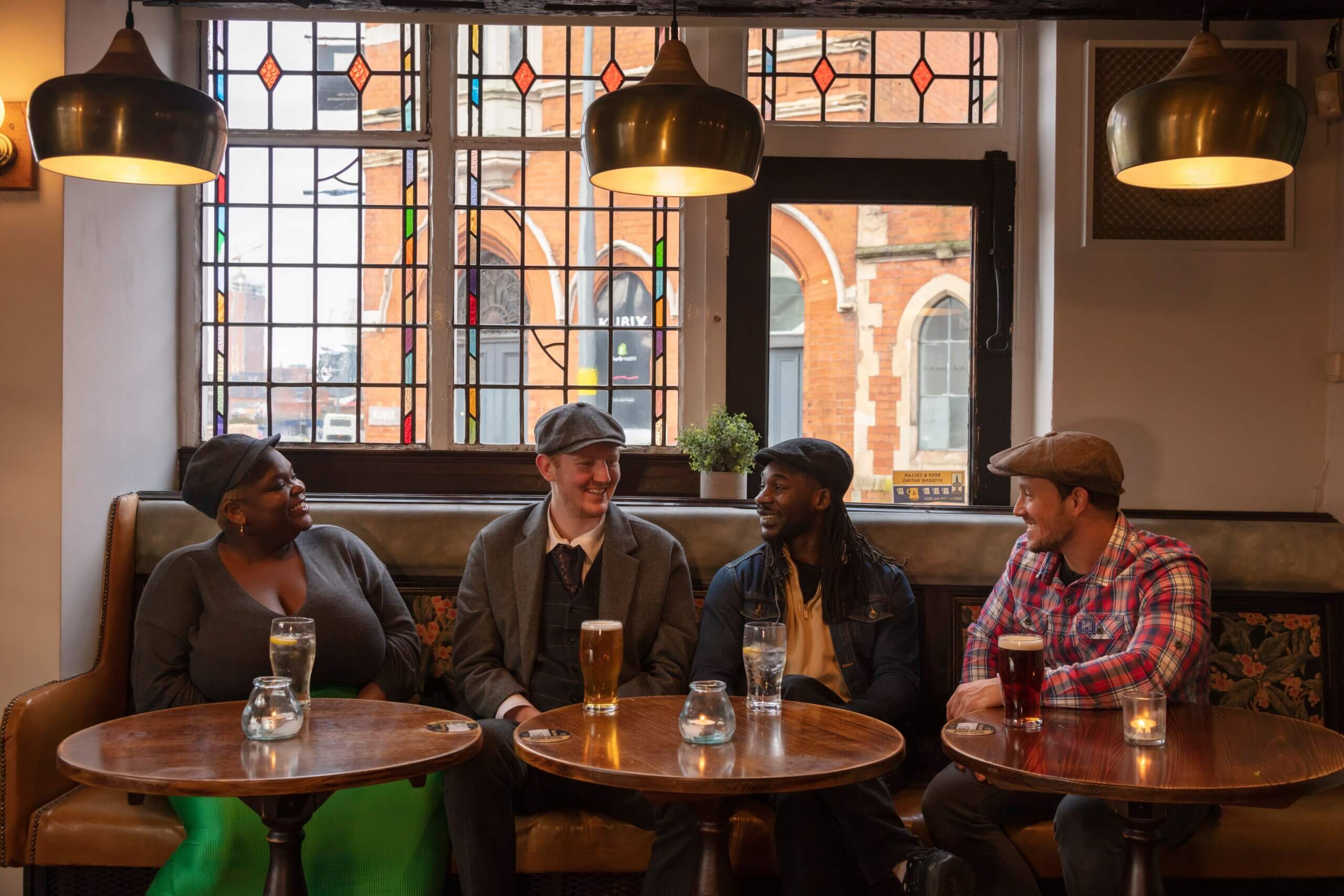 Four friends sat by the window and having a drink at The Old Crown Pub in Deritend, Digbeth, Birmingham